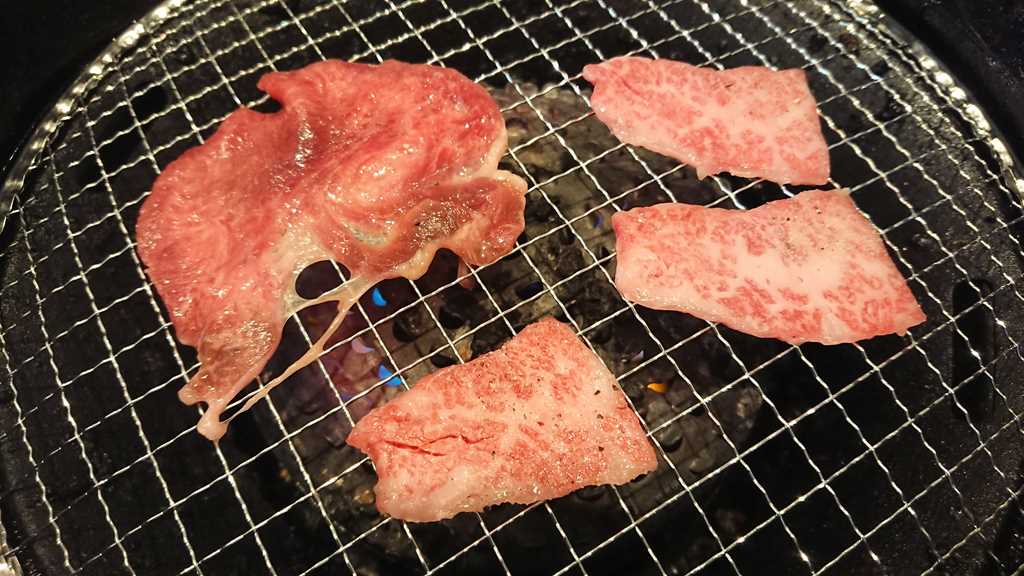 熟成焼肉いちばんのプレミアムコースで最初に提供される肉の盛り合せの黒毛和牛カルビと牛タンを焼いているようす