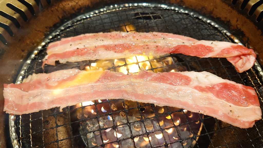 焼肉宝島の宝島スペシャルコース以上から注文できる「とろけるジュレのすき焼き風カルビ」を焼いているようす
