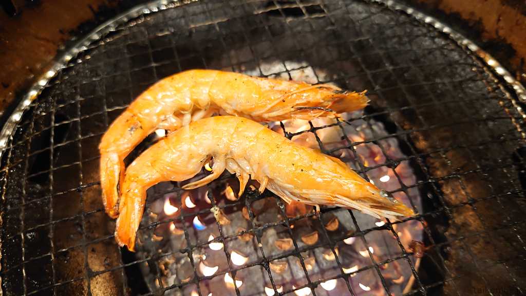 焼肉宝島の宝島スペシャルコース以上から注文できる「殻付き有頭海老焼き」を焼いているようす